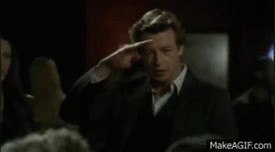 Man In Suit And Tie Standing Before Crowd In Dark Room GIF