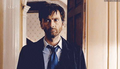 Man In Suit And Tie Standing By ITV Door GIF