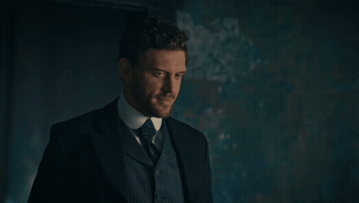 Man In Suit And Tie Standing In Dark Room GIF
