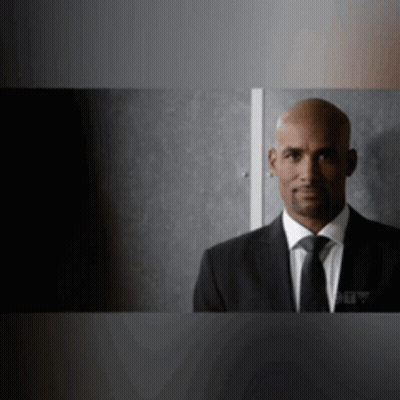 Man In Suit And Tie Standing In Dark Room GIF