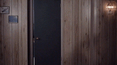 Man In Suit And Tie Standing In Doorway In Wood Paneled Room GIF