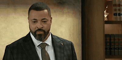 Man In Suit And Tie Standing In Front Of Bookshelf GIF