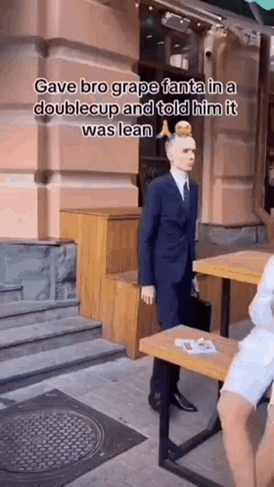 Man In Suit And Tie Standing In Front Of Building And Table GIF