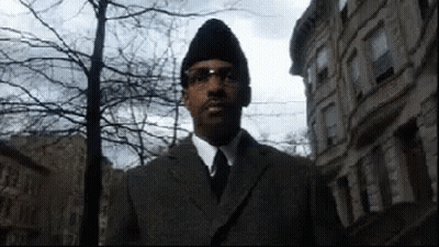 Man In Suit And Tie Standing In Front Of Buildings GIF