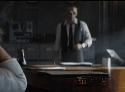 Man In Suit And Tie Standing In Front Of Desk With Letter P GIF