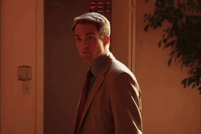 Man In Suit And Tie Standing In Front Of Door Saying Rec GIF
