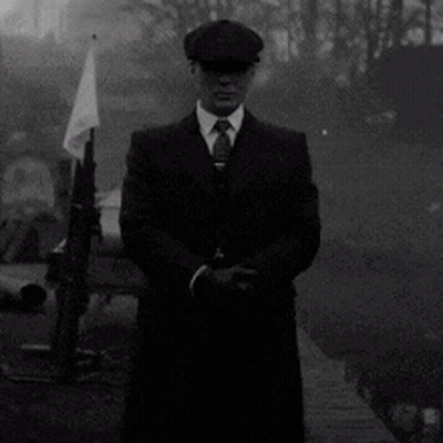 Man In Suit And Tie Standing In Front Of Flag And Gun GIF
