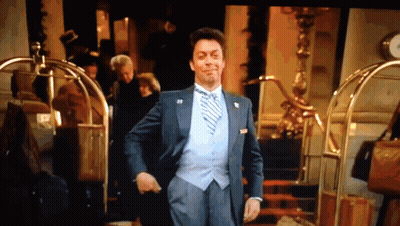 Man In Suit And Tie Standing In Front Of Hotel GIF