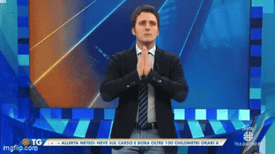 Man In Suit And Tie Standing In Front Of Screen Saying TG GIF
