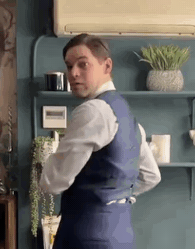 Man in Suit and Tie Standing in Front of Shelf With Plants