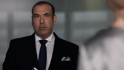 Hombre con traje y corbata de pie frente a una ventana GIF