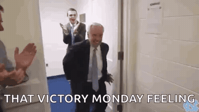 Man In Suit And Tie Standing In Hallway With Other Men GIF