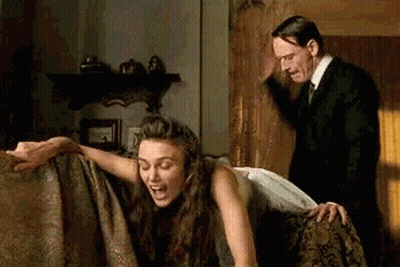 Man In Suit And Tie Standing Next To Woman On Couch GIF