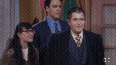 Man In Suit And Tie Standing Next To Woman With Glasses GIF