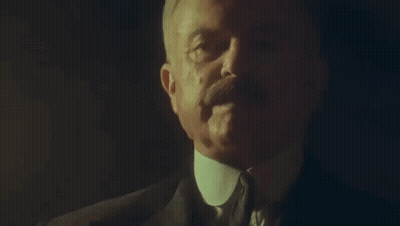 Man In Suit And Tie Talking In Dark Room GIF