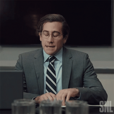 Man In Suit And Tie Typing On Laptop With SNL Logo GIF