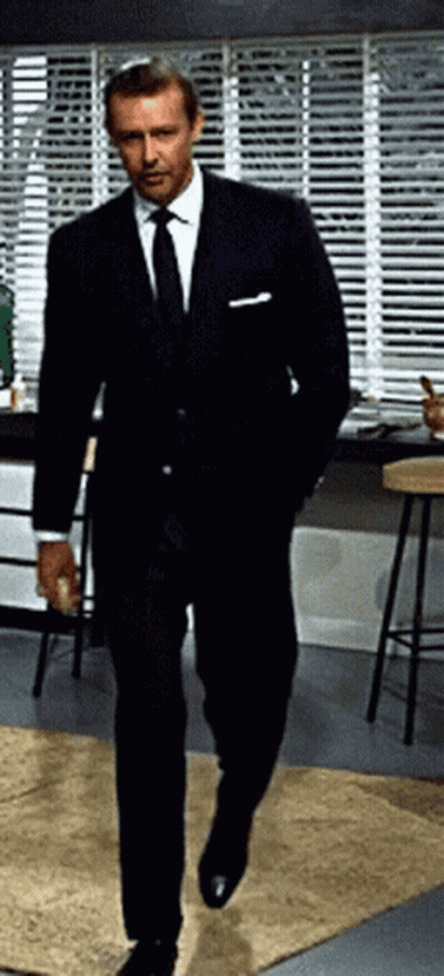 Man In Suit And Tie Walking By Window With Blinds GIF