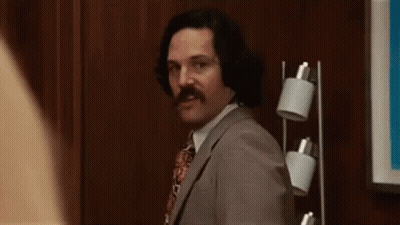 Man In Suit And Tie Waving Near Lamp GIF