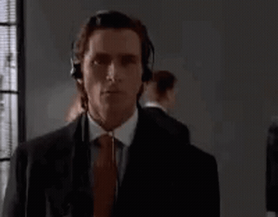 Man In Suit And Tie Wearing Headphones By Window GIF