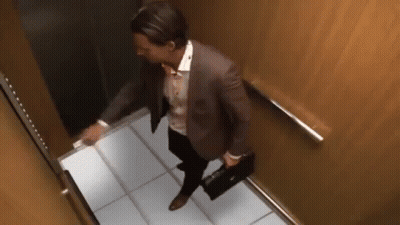 Man In Suit And Tie With Briefcase Walking Down Elevator GIF