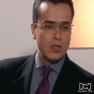 Man In Suit And Tie With Nuestra Tele Logo GIF