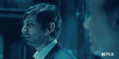 Man In Suit And White Shirt Standing In Dark Room With Netflix Logo GIF