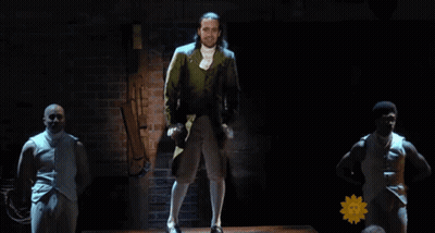 Man in Suit and White Socks on Stage With Two Men