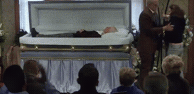 Man In Suit And Woman Beside Coffin GIF