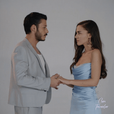 Man In Suit And Woman In Blue Dress Holding Hands In Front Of Cam Sign GIF