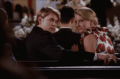 Man In Suit And Woman In Floral Dress Sitting On Bench GIF