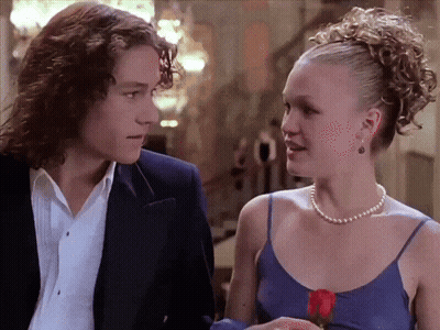 Man In Suit And Woman In Pearl Necklace Looking At Each Other GIF