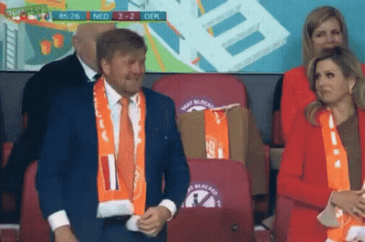 Man In Suit And Woman In Red Jacket At Stadium GIF