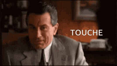 Man In Suit At Desk Saying Touché GIF