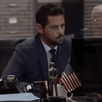 Man In Suit At Desk With American Flag GIF