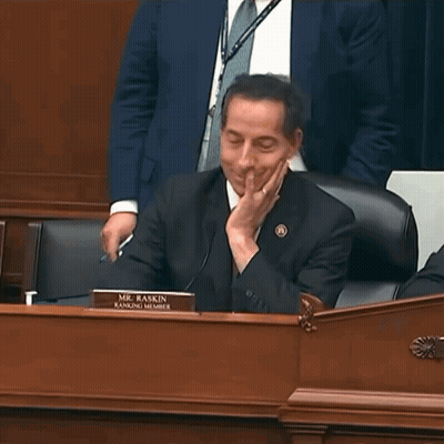 Man in Suit at Desk With Mr. Raskin Ranking Member Sign
