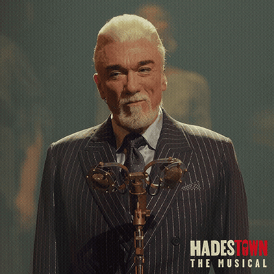 Man In Suit At Microphone Hadestown Musical Red Text GIF