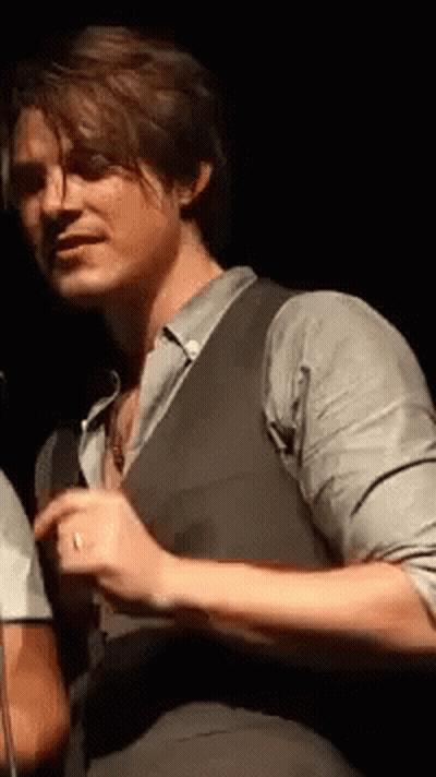 Man In Suit At Microphone In Dark Room GIF