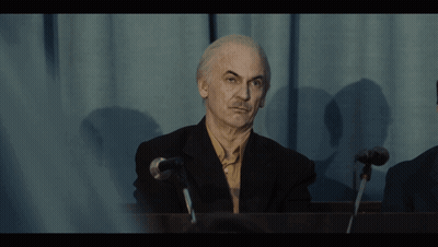 Man In Suit At Microphone In Dark Room GIF
