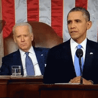 Man In Suit At Microphone With Seated Man GIF
