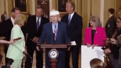 Man in Suit at Podium with Bandaged Head