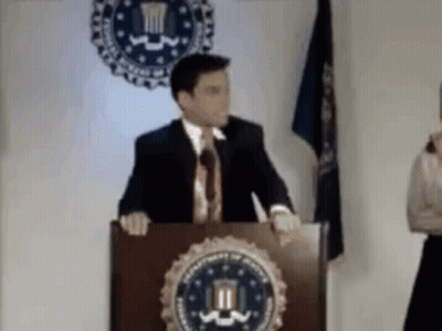 Man In Suit At Podium With DOJ Seal GIF