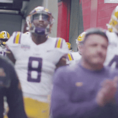 Man In Suit At Podium With LSU Sign GIF
