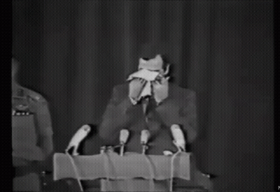 Man In Suit At Podium With Microphones GIF