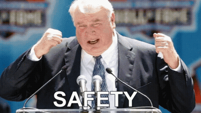 Man In Suit At Podium With Safety Above GIF
