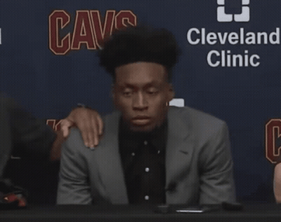 Man In Suit At Table In Front Of Cleveland Clinic Sign GIF