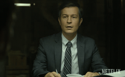 Man In Suit At Table With Netflix Logo GIF