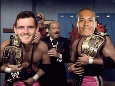 Man In Suit Behind Two Wrestlers Holding Belts GIF