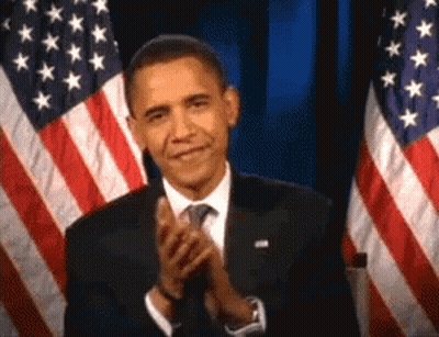 Man In Suit Clapping In Front Of Two American Flags GIF