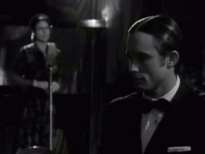 Man In Suit Clapping While Woman At Microphone Black And White GIF