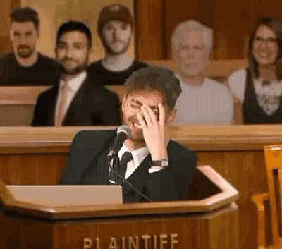 Man In Suit Covering Face At Podium GIF